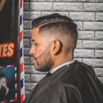 Profile view of a man with a stylish haircut in a barber shop.